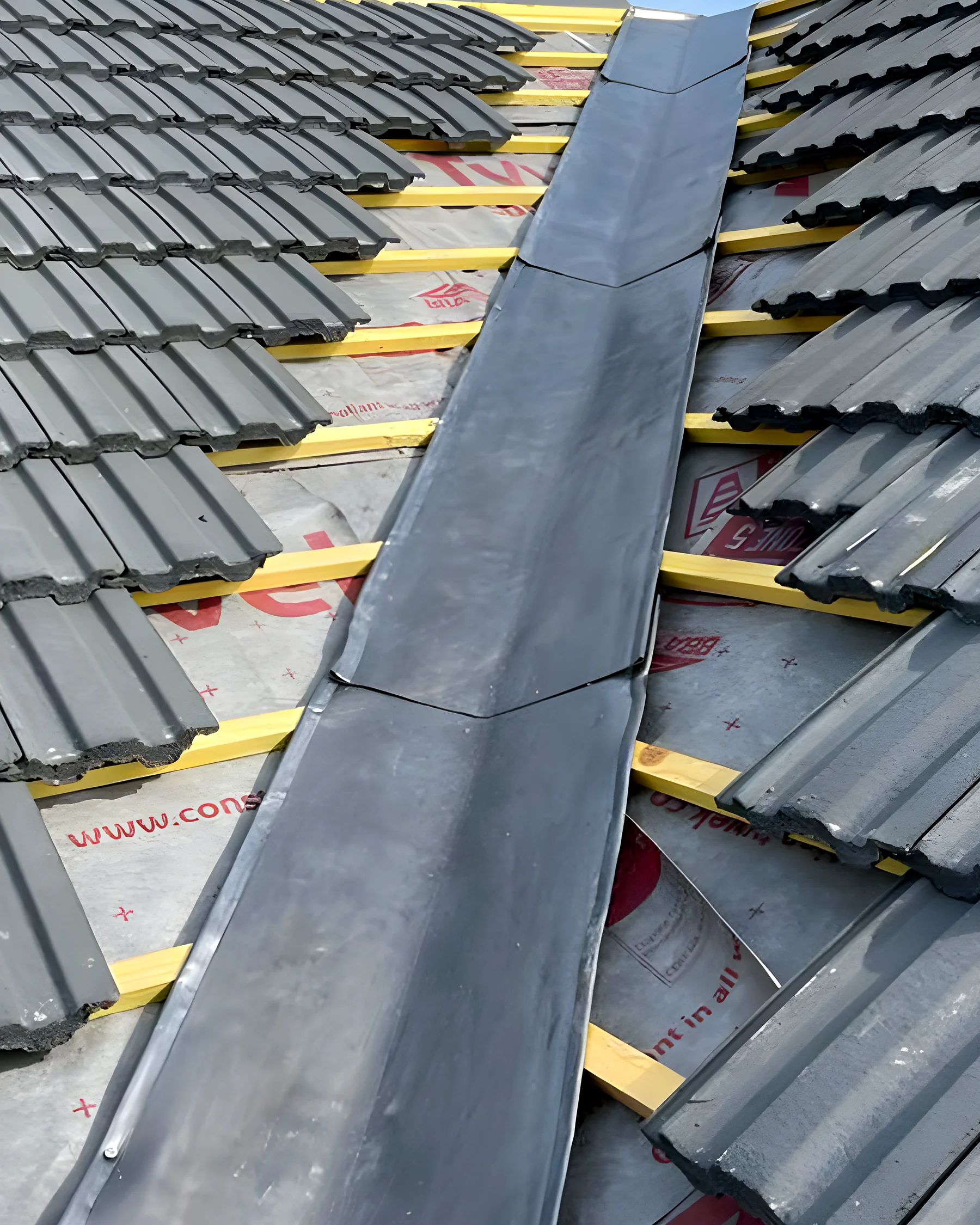 Roofer dressing a lead valley on a tiled roof