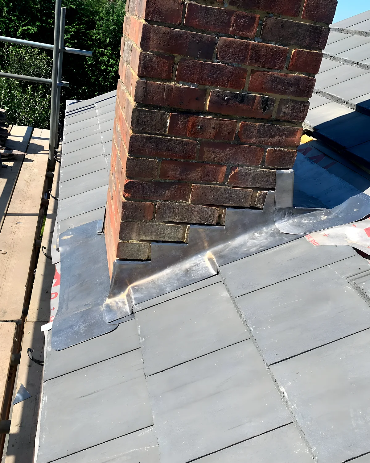 Freshly dressed lead valley set between two runs of grey roof tiles