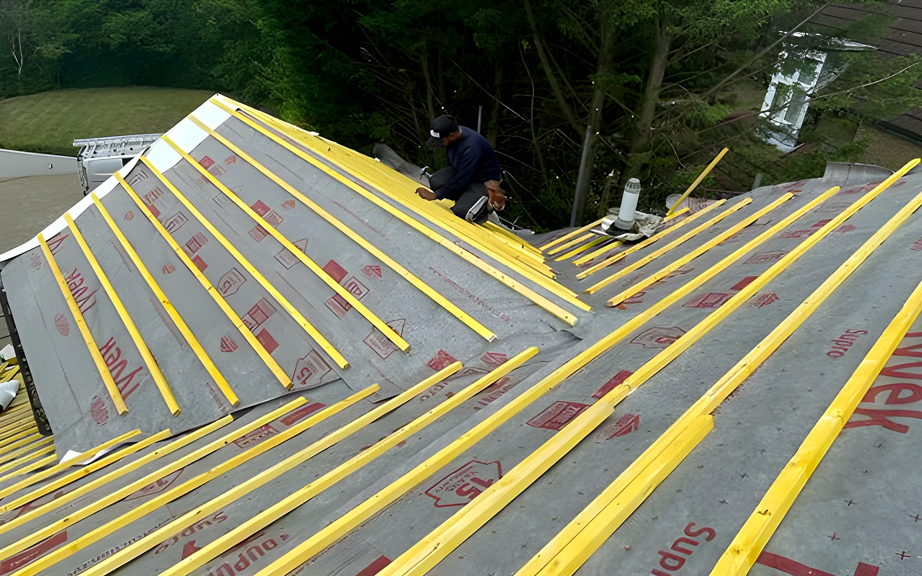 A roofer fitting membrane over new rafters
