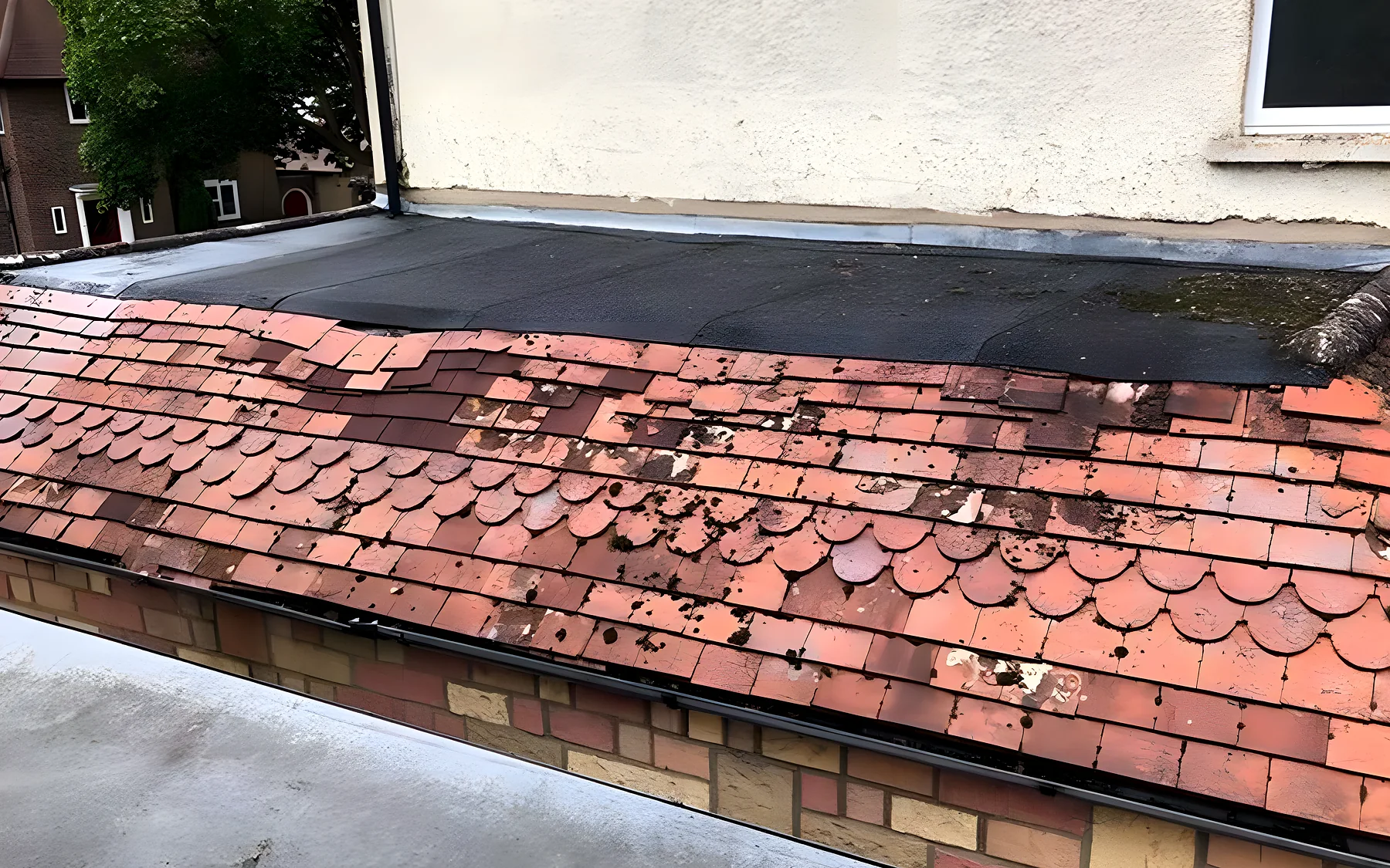 Old clay plain tiles and moss above a flat roof, before the work