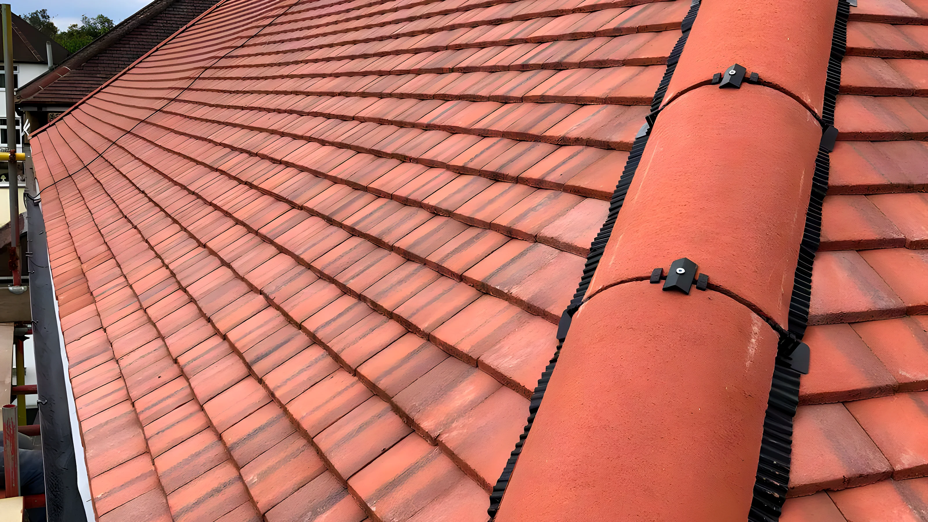 Terracotta clay tiled roof with a bedded ridge running up to the apex