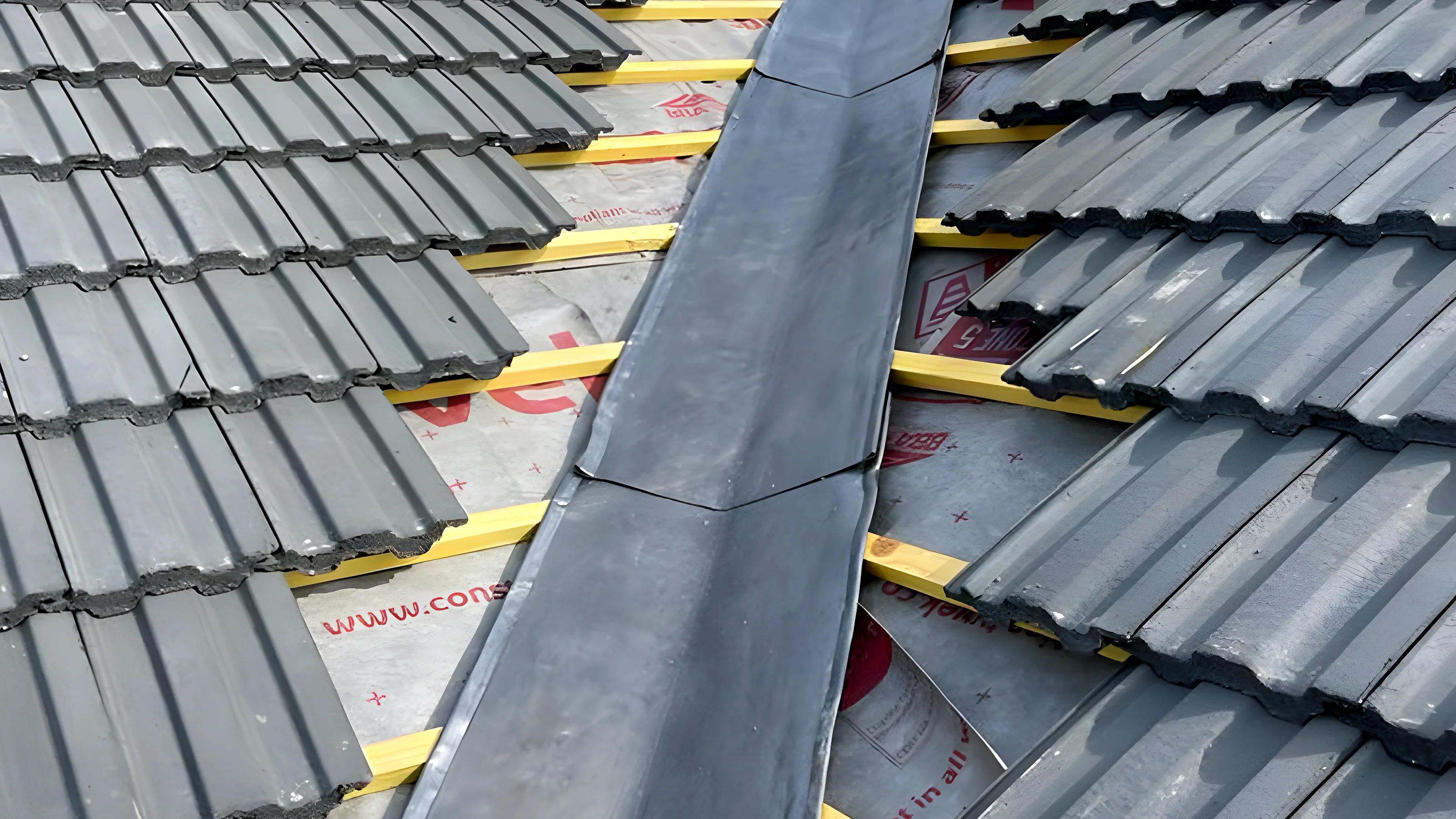 Freshly dressed lead valley set between two runs of grey roof tiles