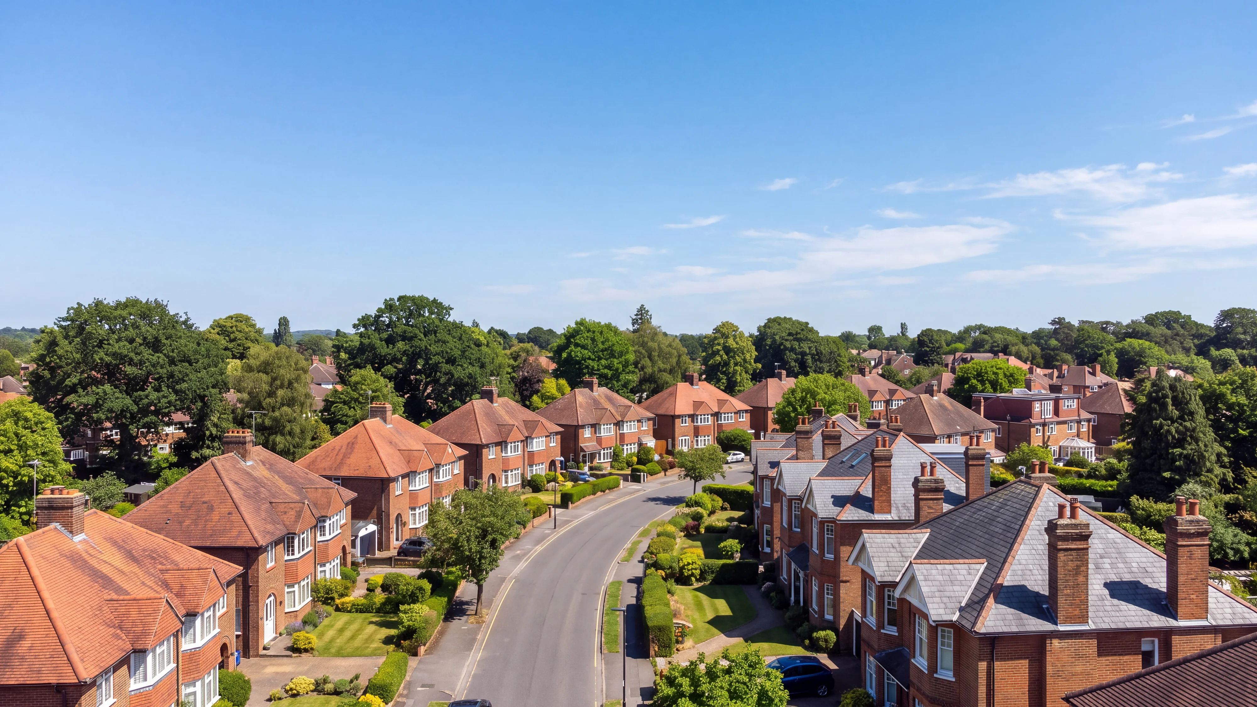 A leafy Surrey street of 1930s houses with clay tile roofs and Victorian villas in slate, from above