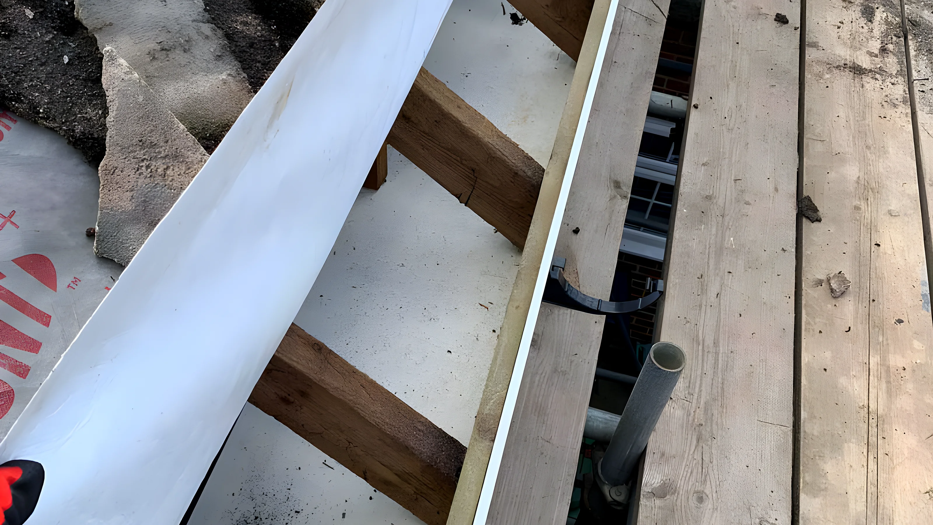 Roofer on a ladder fitting new white uPVC fascia and guttering to a brick house