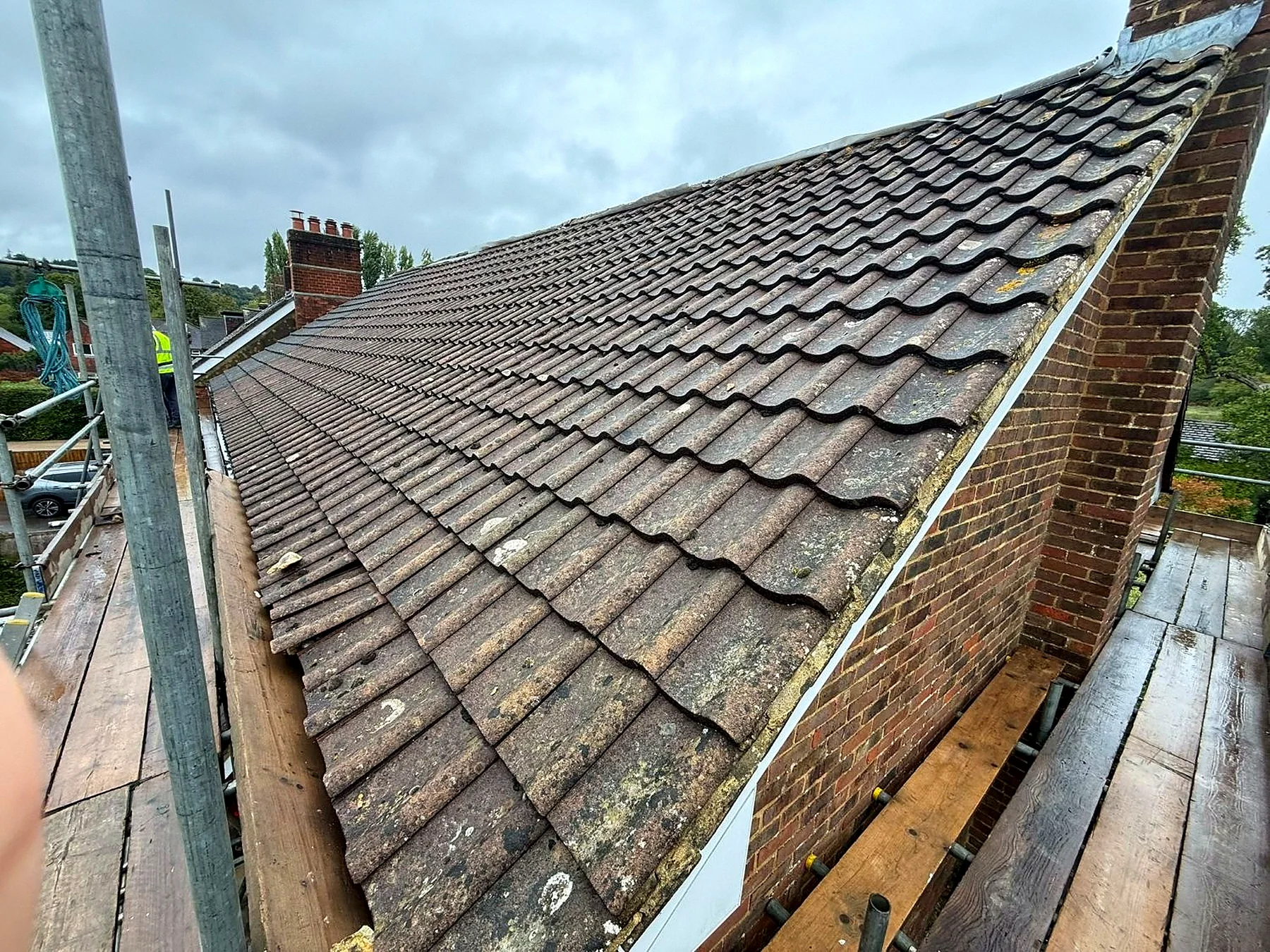 The same roof before the work, the old tiles pitted and covered in moss