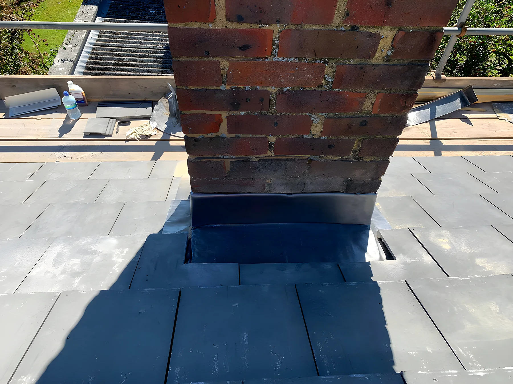 A chimney with new lead flashings on a slate roof