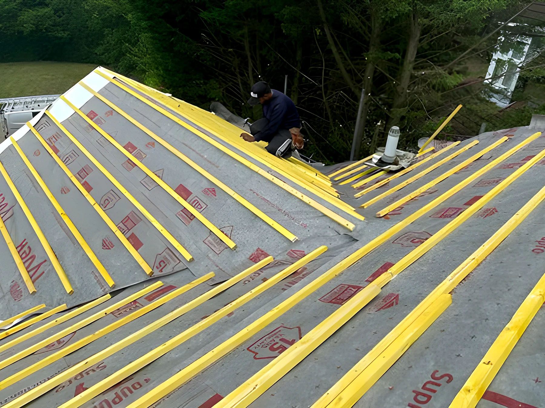 A roofer fitting membrane over new rafters
