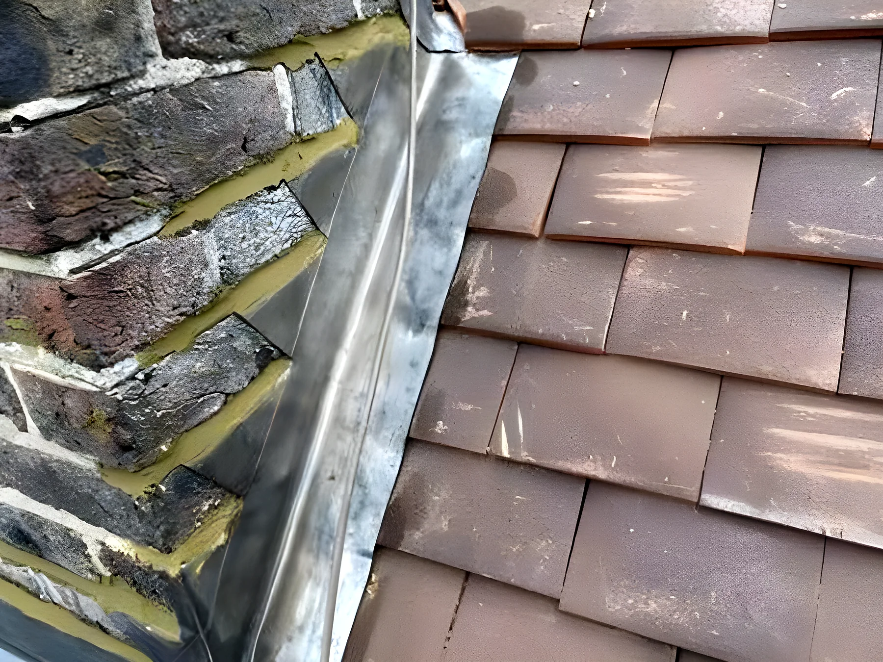 Lead flashing dressed against a chimney on a clay tiled roof