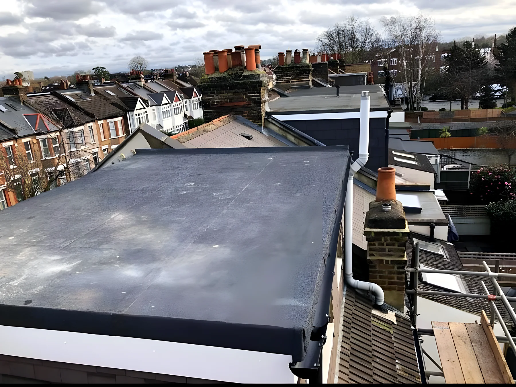 A finished GRP roof over a terraced house, chimneys beyond