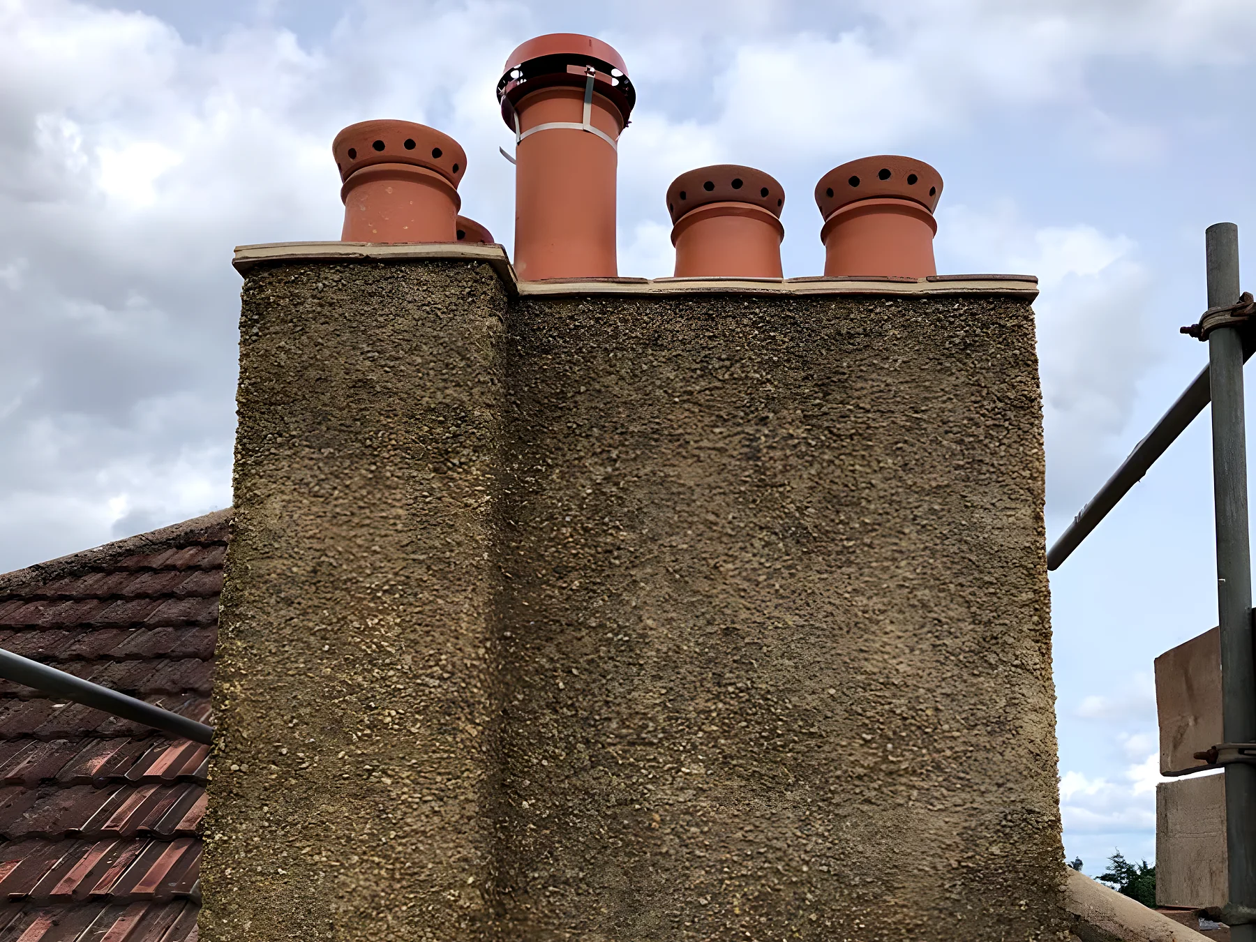 Rendered chimney stack with four clay pots against the sky