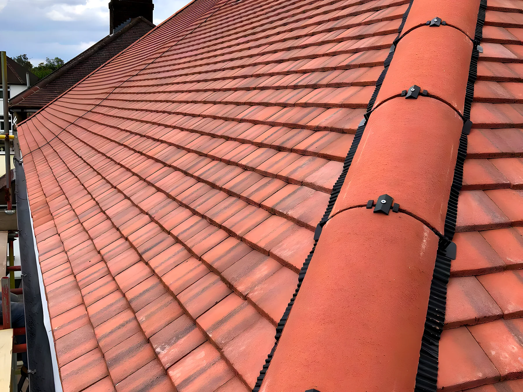 Terracotta clay tiled roof with a freshly bedded ridge