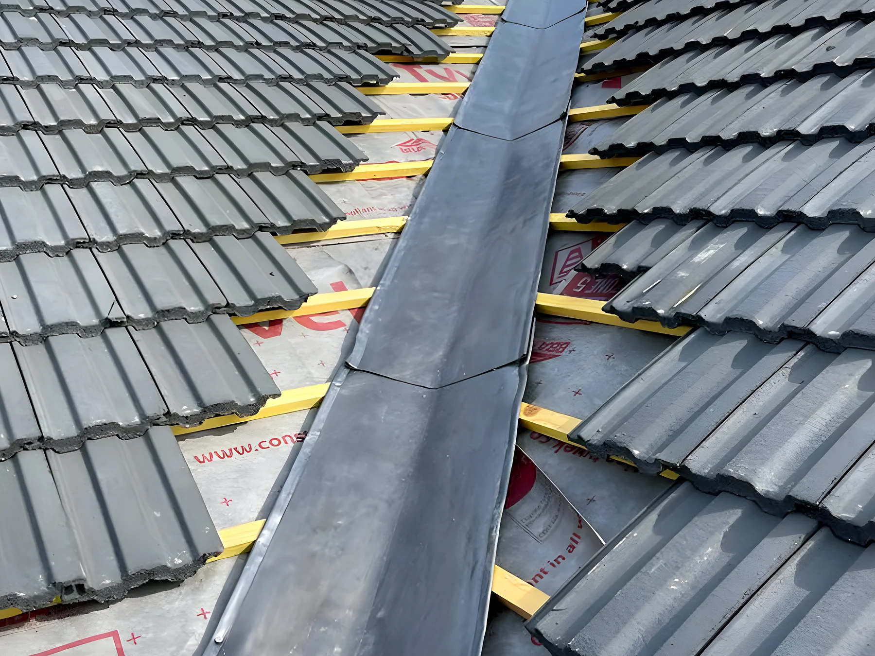 New lead valley dressed between two runs of grey roof tiles